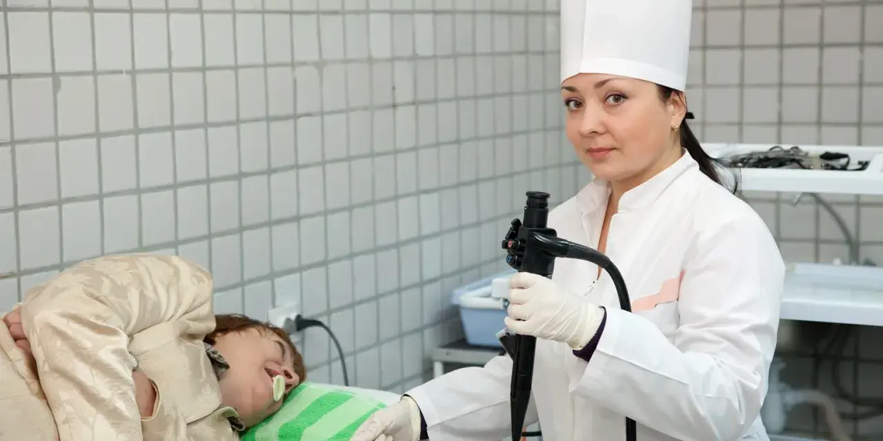 Lekarka przygotowuje pacjenta do gastroskopii. Przed badaniem ważne jest, co można jeść dzień przed gastroskopią – zazwyczaj lekkostrawne posiłki.