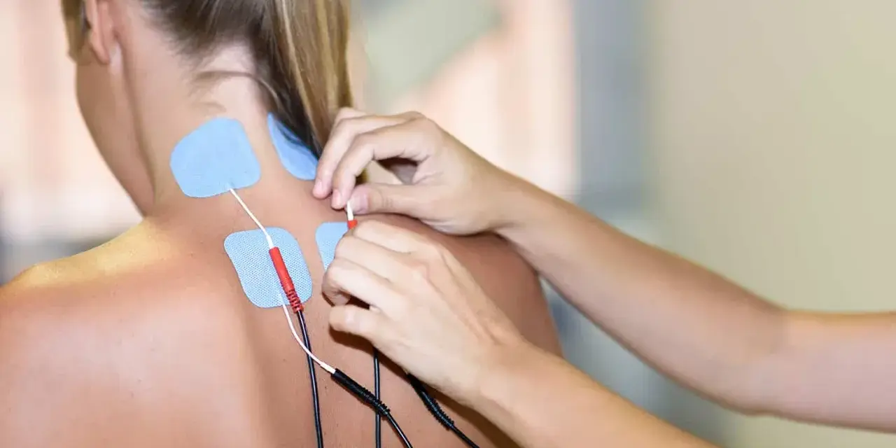 Elektrody na karku i plecach pacjentki, przygotowywane do zabiegu prądami na kręgosłup.