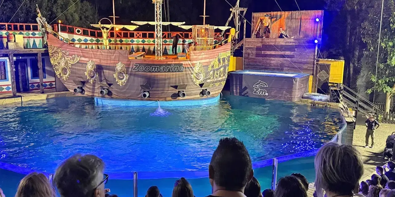 A pirate ship show at Zoomarine Roma with performers on a stage and in the water.