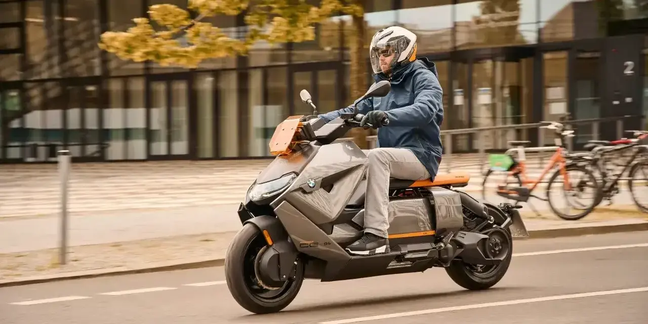 Mężczyzna w kasku jedzie na futurystycznym skuterze BMW CE04 po mieście.