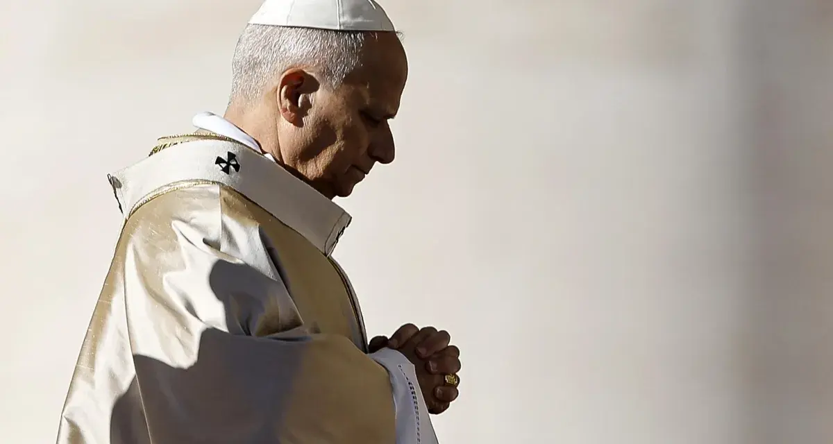 Papież w białej piusce i złotej szacie modli się, wierzę w boga. W jego oczach widać głęboką wiarę.