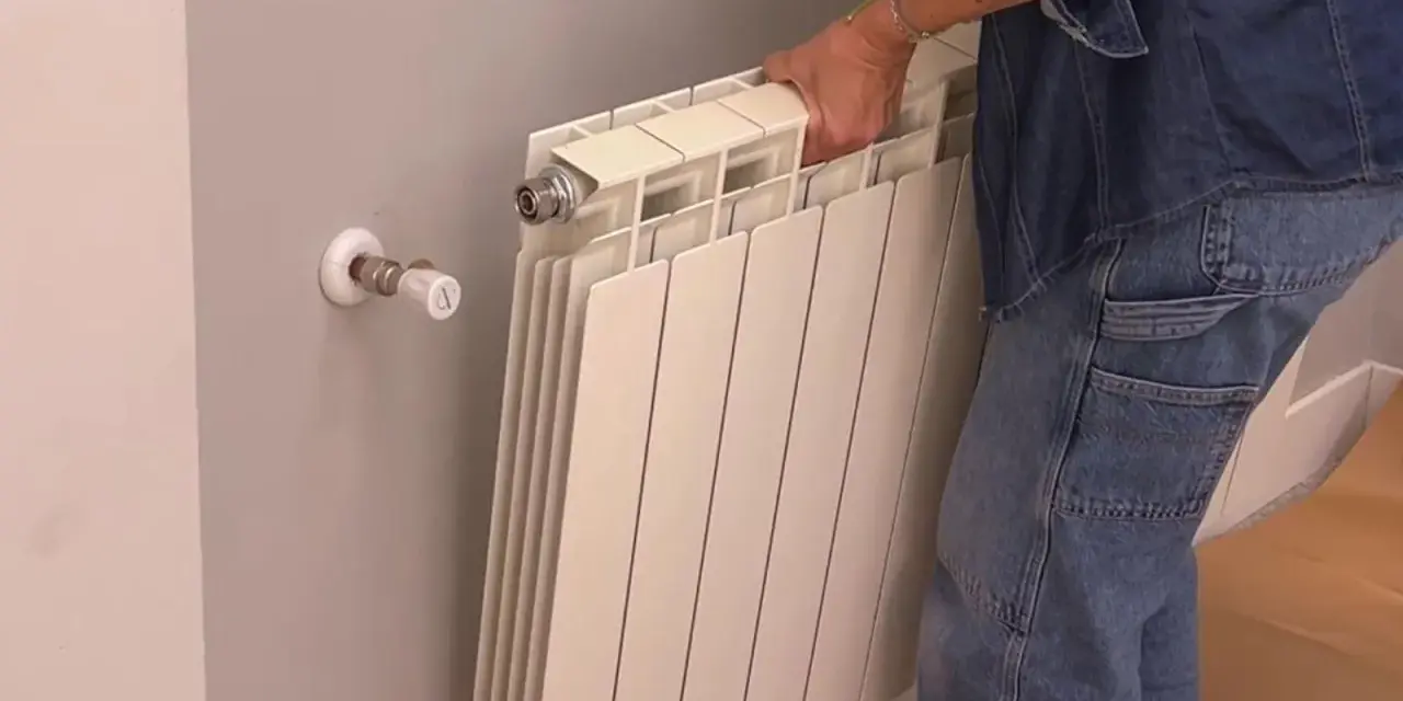 Persona quitando radiadores para pintar la pared.