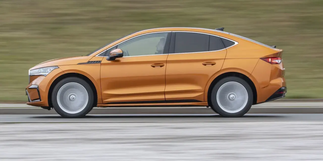 Pomarańczowy elektryczny SUV coupe w ruchu, widok z boku.