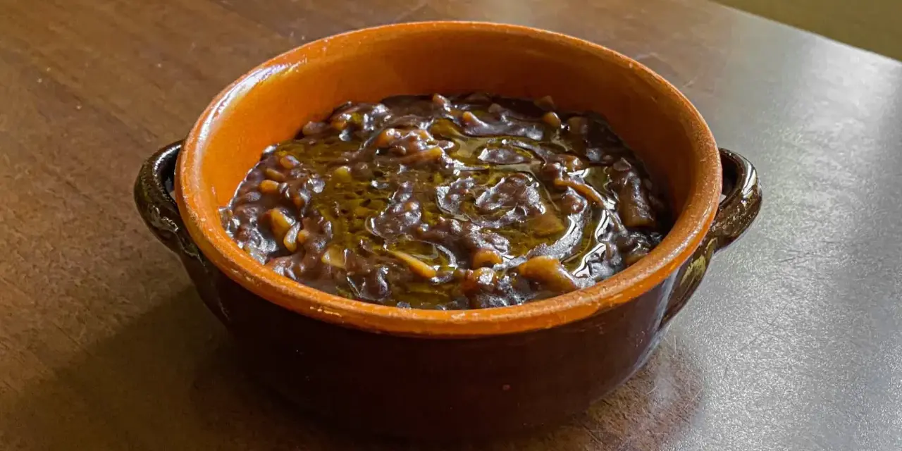 Una ciotola di terracotta con un saporito piatto di pasta e lenticchie, condito con olio d'oliva.