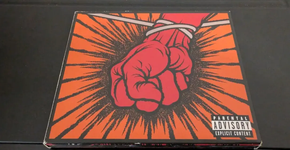 Okładka płyty Metallica "St. Anger" z czerwoną, zawiązaną pięścią i napisem "Parental Advisory".