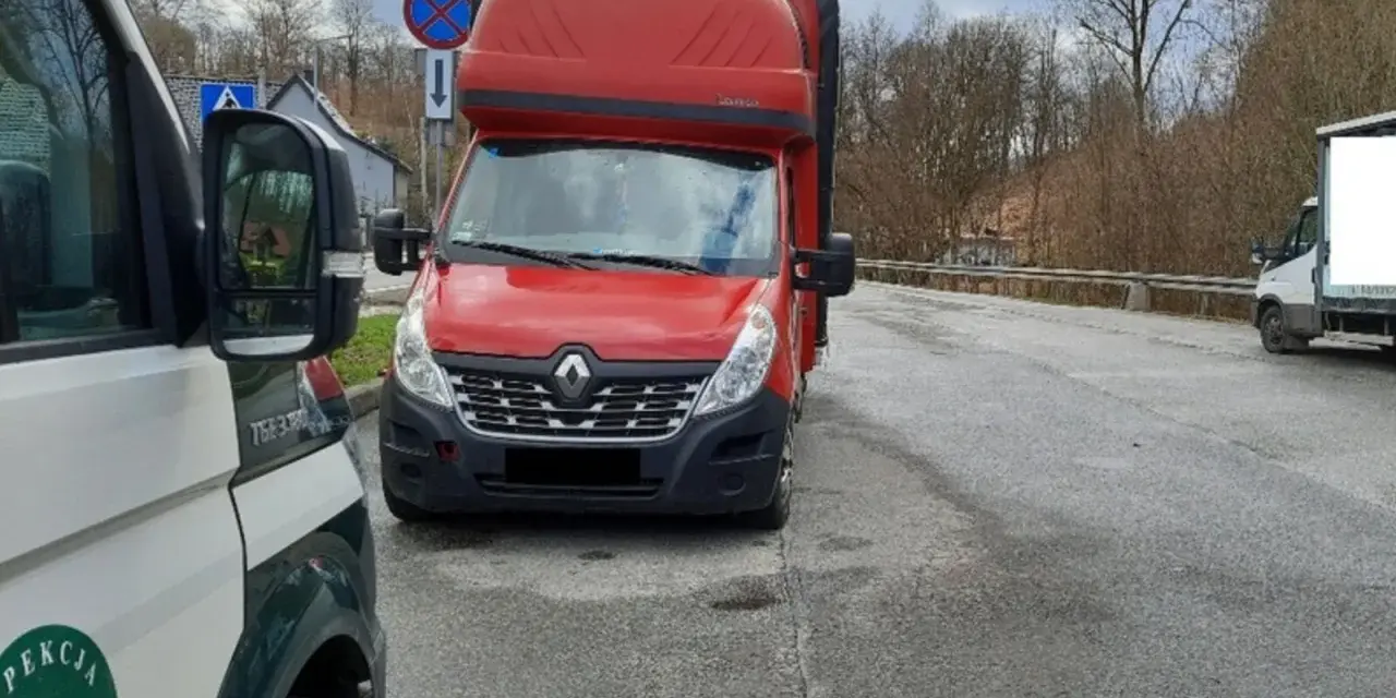 Czerwony bus Renault na drodze, obok pojazd inspekcji. Może to być związane z wnioskiem o wypis z licencji transportowej.