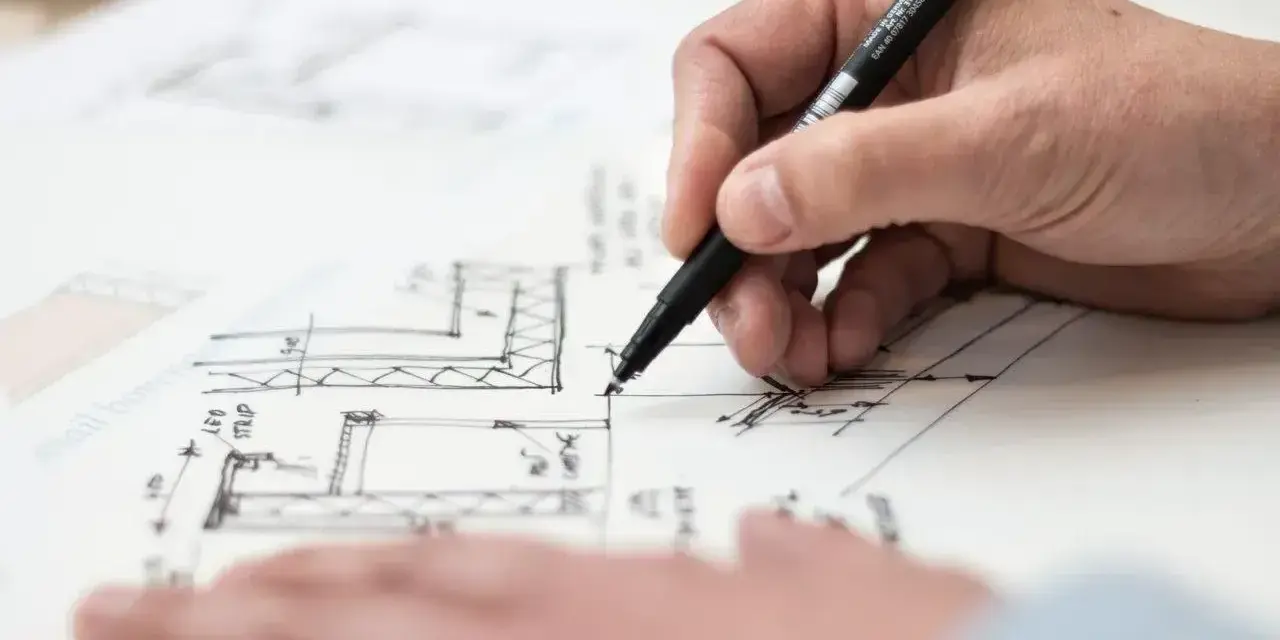 Dłoń rysuje plany architektoniczne, uwzględniając objętość właściwą.