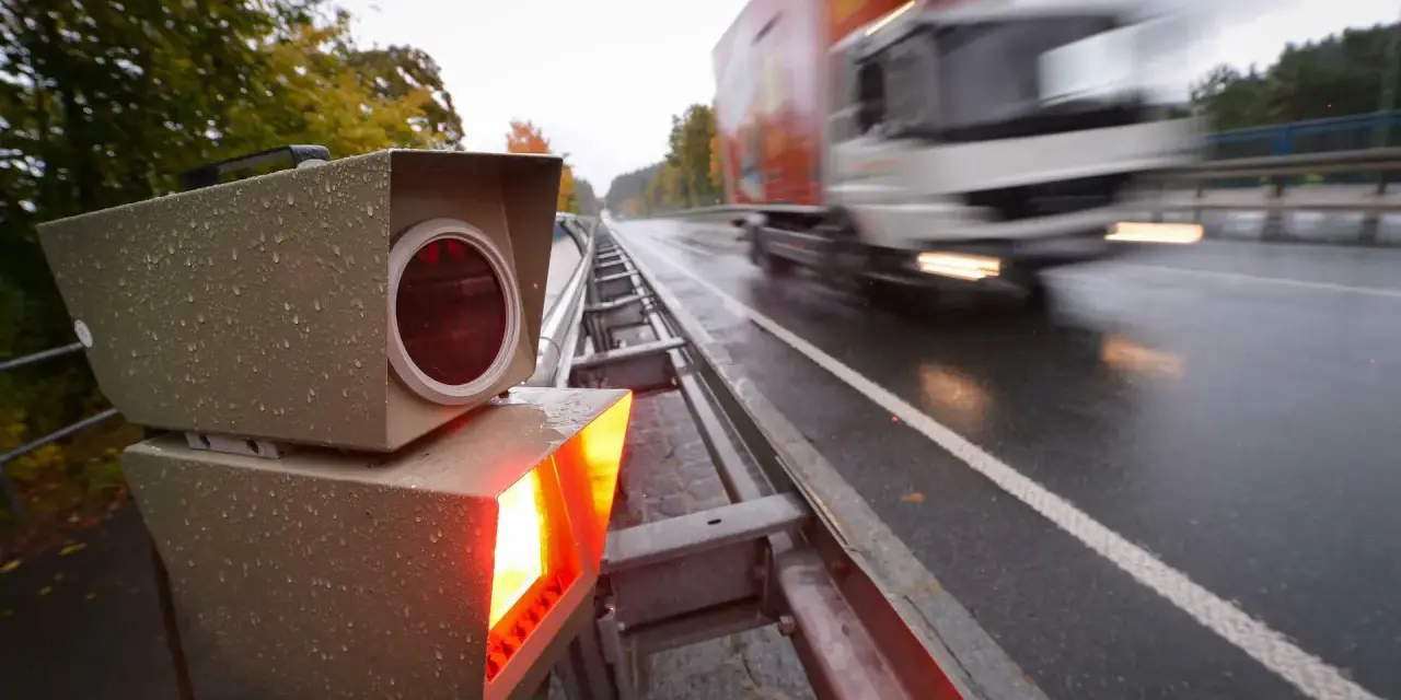 Blitzlicht erhellt die nasse Fahrbahn. Ein LKW rast vorbei. Das Zeugnisverweigerungsrecht bei Blitzern ist ein Thema für Fahrer.