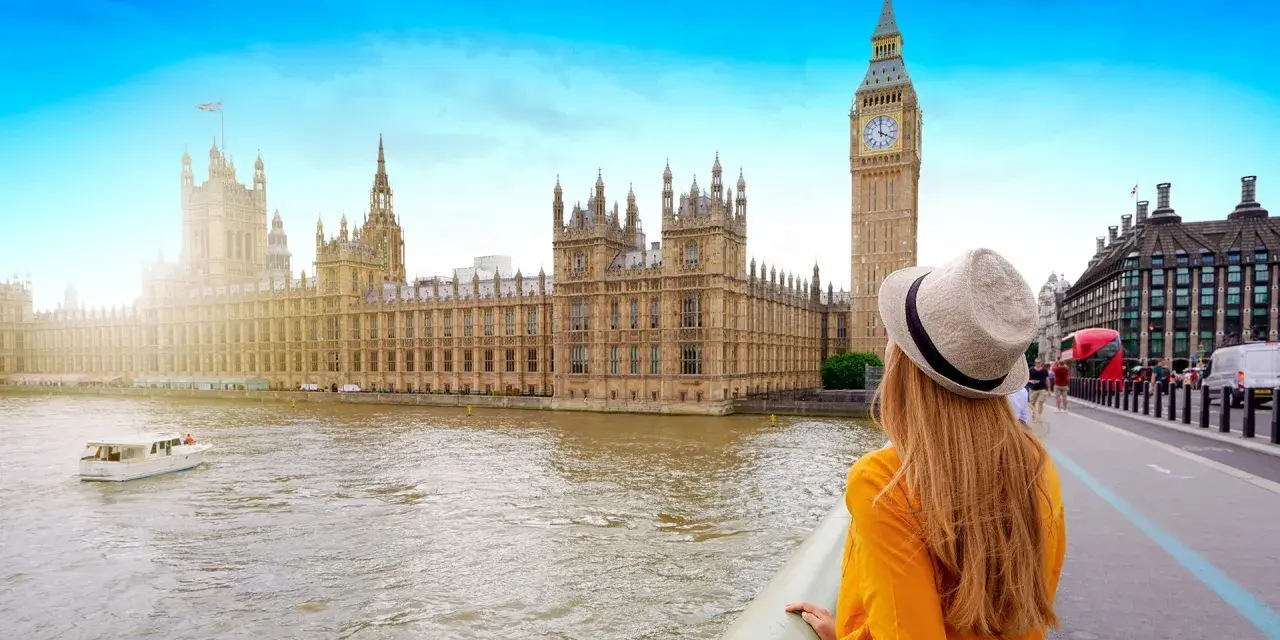 Kobieta w kapeluszu podziwia Pałac Westminsterski i Big Ben, marząc o wizie do Londynu.