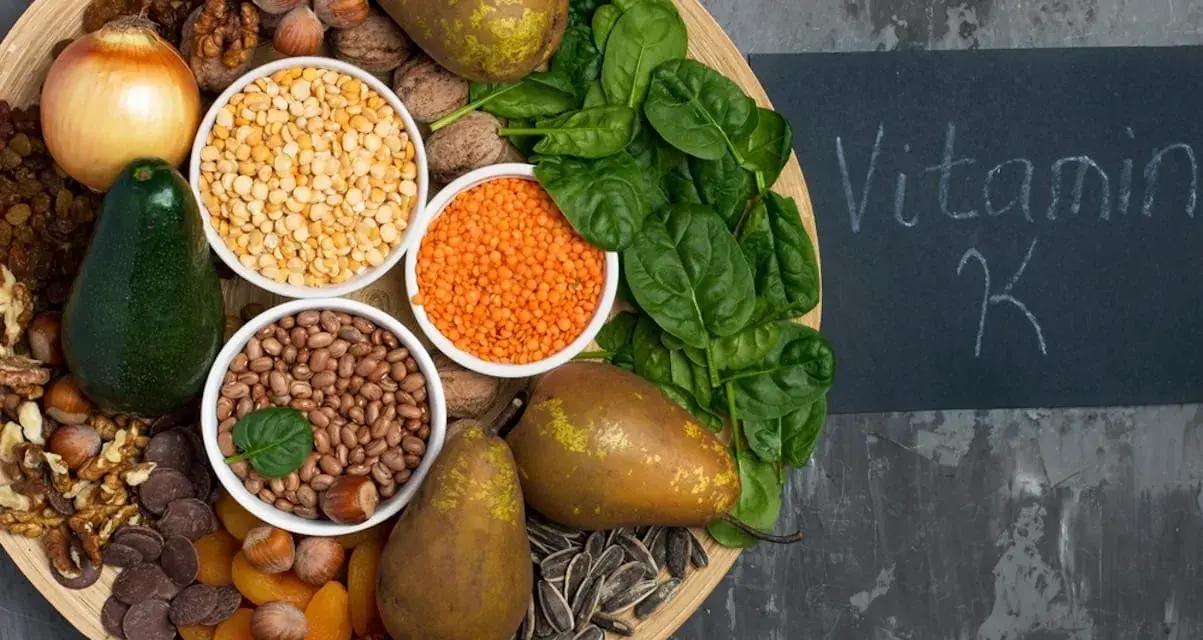 En bricka med mat rik på vitamin K1: spenat, päron, avokado, nötter, linser, bönor, torkade aprikoser, solrosfrön och choklad.