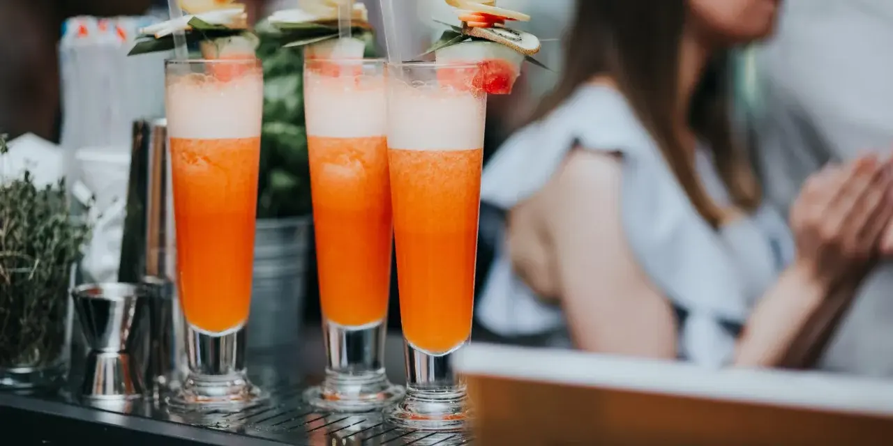Orzeźwiający drink dla kobiet, ozdobiony owocami i listkami, gotowy do podania na letnim przyjęciu.