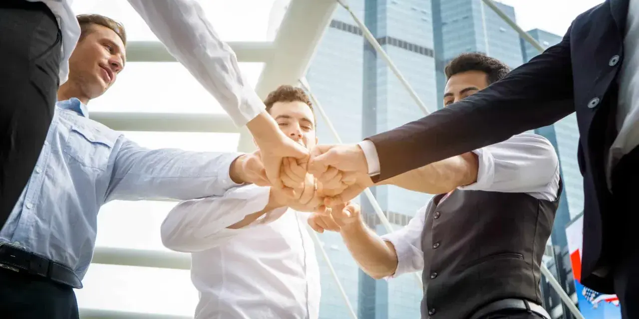 Un gruppo di uomini d'affari unisce i pugni, mostrando le loro caratteristiche personali di unità e determinazione.