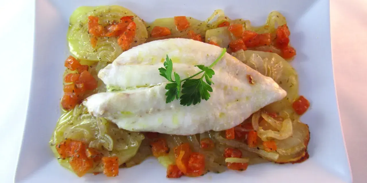 Filete de pescado blanco sobre patatas y zanahorias asadas, un delicioso gallo al horno.