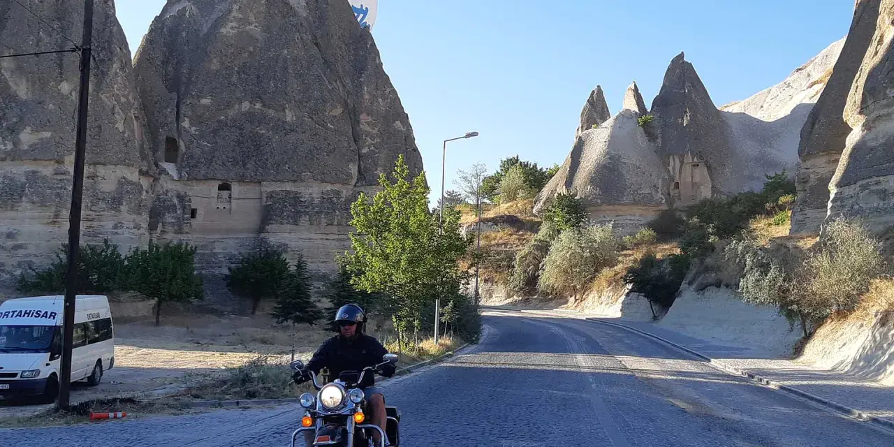 Niesamowita podróż motocyklem przez Kapadocję w Turcji. W tle widać latający balon i skalne formacje.