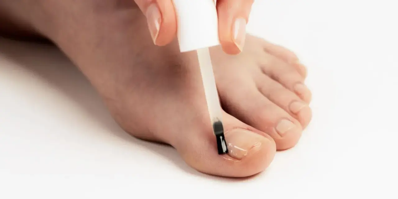 Application d'un soin transparent sur un ongle abîmé pour le protéger et le renforcer.