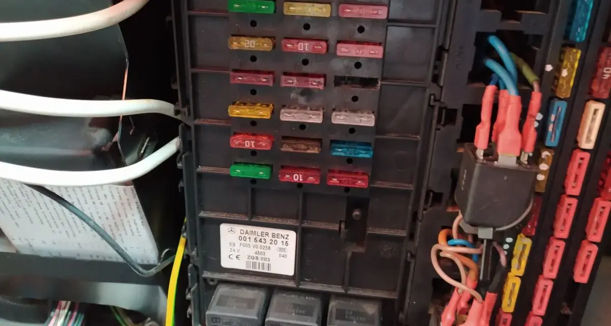 Panel bezpieczników w Mercedesie GL. Widoczne bezpieczniki i przekaźniki, a także etykieta z opisem.