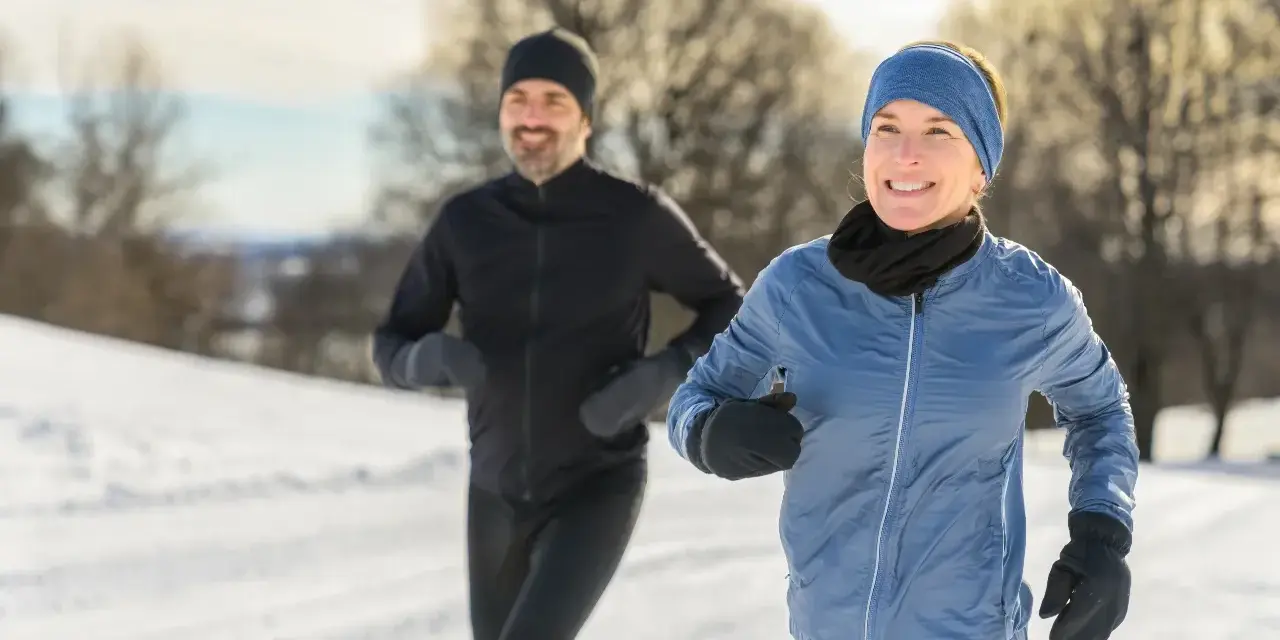 Ein Paar genießt das Laufen im Winter. Sie tragen passende Winterkleidung, um sich warm zu halten.