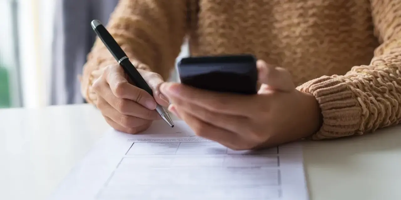 Kobieta z telefonem w dłoni wypełnia formularz, dokonując zgłoszenia darowizny online.