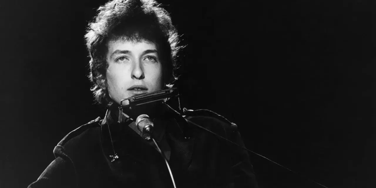 Bob Dylan spielt Mundharmonika, ein wahrer "rolling stone" auf der Bühne, mit seinem charakteristischen Blick.