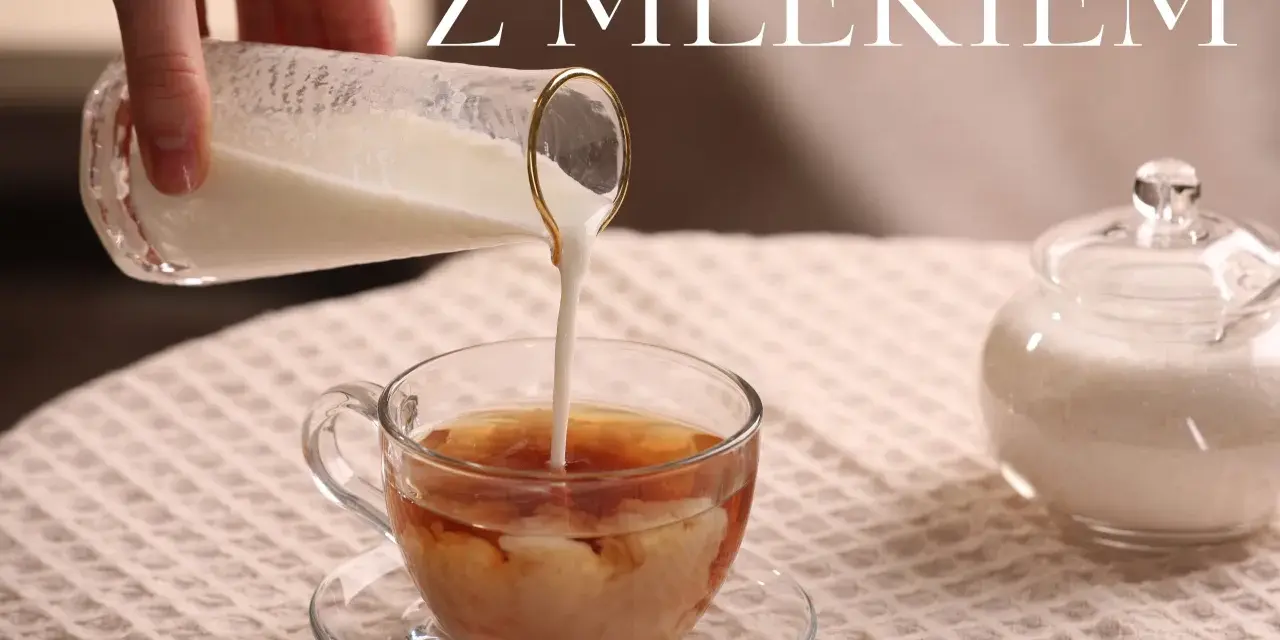 Ręka wlewa mleko do szklanki z herbatą, tworząc piękne smugi. Obok stoi cukiernica. Idealna herbata z mlekiem na chłodny dzień.