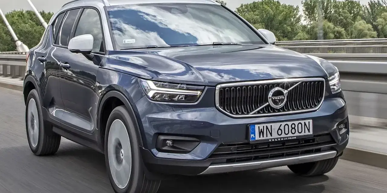 Ciemnogranatowy Volvo XC40 jedzie po moście. Sprawdź aktualną volvo xc40 cena i ofertę.