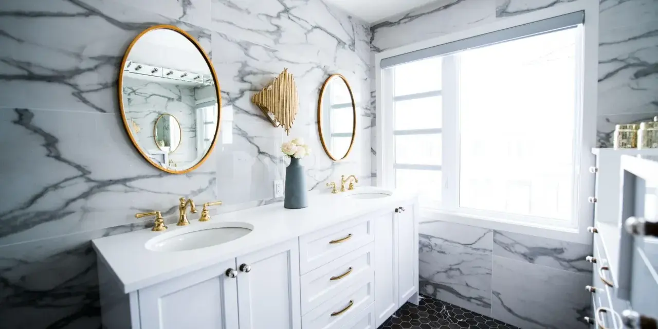 Bagno moderno con marmo, doppio lavabo e rubinetteria oro. Un'idea per capire quanto costa piastrellare un bagno di 5 mq.