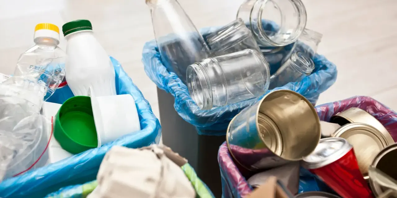 Segregacja odpadów: szklane słoiki, plastikowe butelki i puszki czekają na wywóz śmieci.