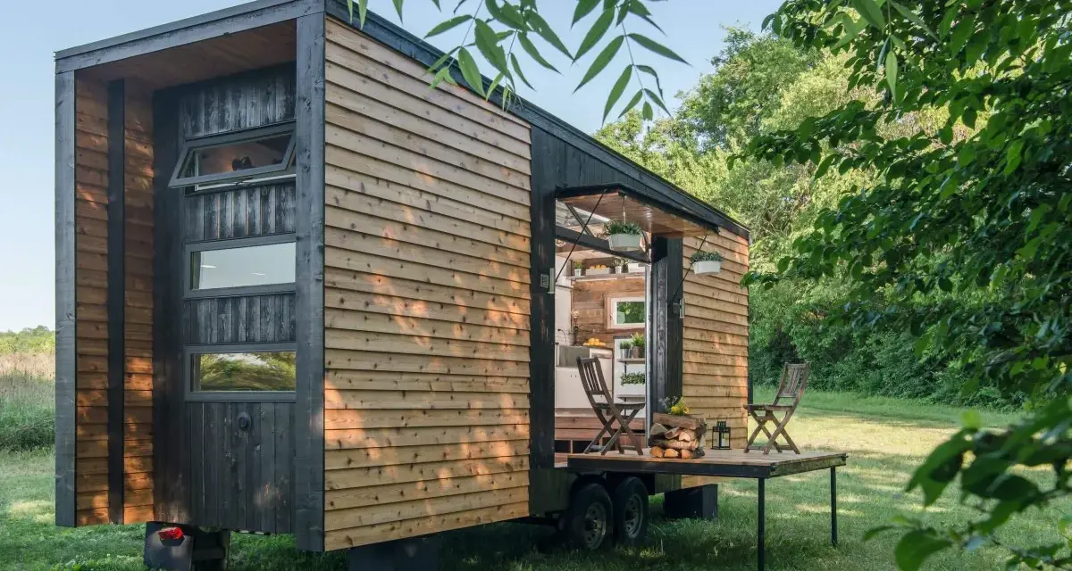 Casa móvil de madera en un terreno no urbanizable, con mesa desplegable y sillas.