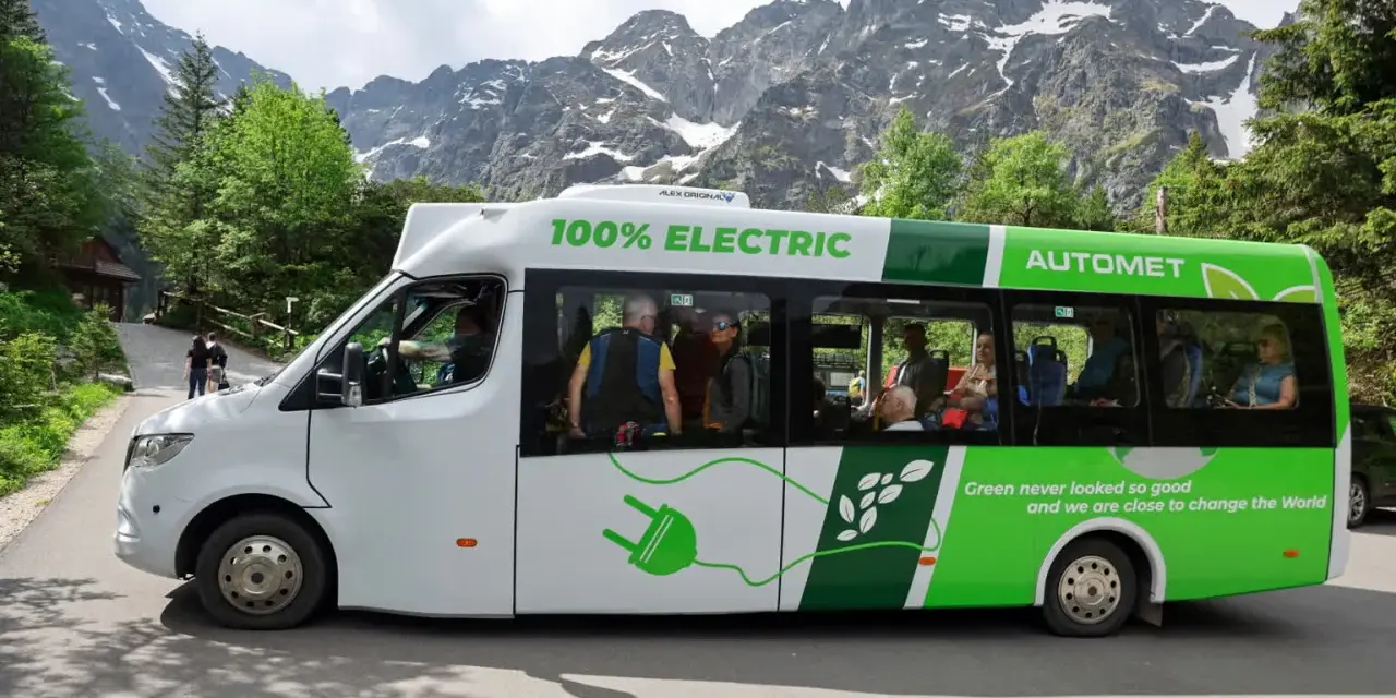 Elektryczny bus na Morskie Oko, z pasażerami w środku, na tle gór.