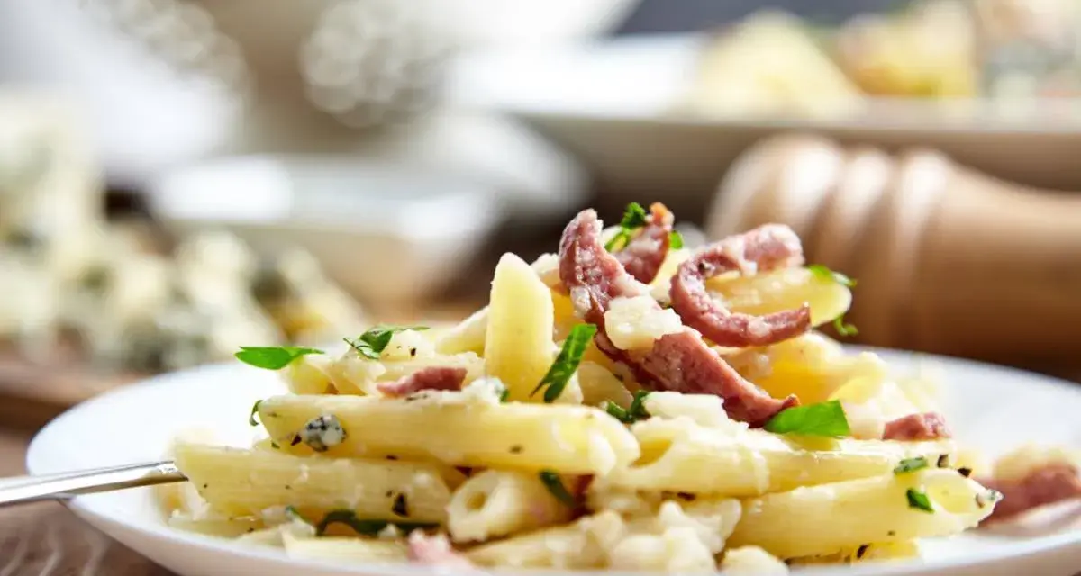 Piatto di pasta porri e salsiccia, cremoso e saporito, con pezzetti di formaggio e erbe fresche.
