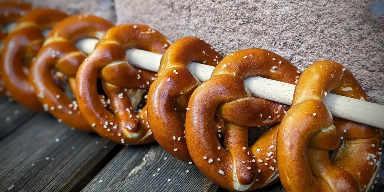 Frisch gebackene Brezeln, perfekt für ein Laugengebäck Rezept. Mit grobem Salz bestreut, liegen sie auf Holzbrettern.
