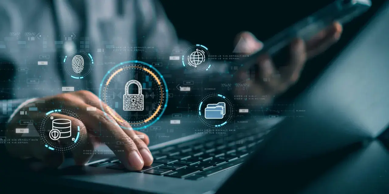 Manos sobre teclado de laptop, con iconos de seguridad digital: candado, huella, base de datos, globo terráqueo. Esto ilustra qué es la seguridad informática.