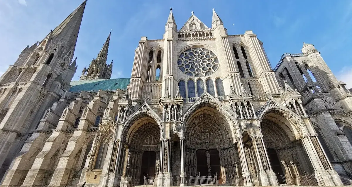 The magnificent Chartres Cathedral, with its iconic rose window and soaring spires, stands majestically against a clear blue sky.