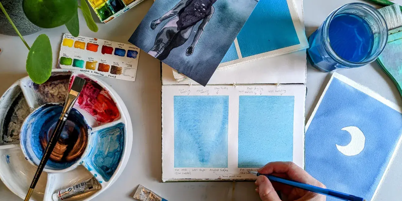 Paleta de acuarelas, pinceles y muestras de pintura azul. Un artista experimenta con técnicas de pintar acuarela.