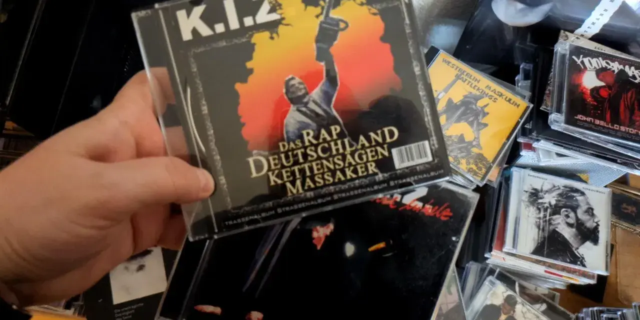 Hand hält CD-Cover von K.I.Z. "Das Rap Deutschland Kettensägen Massaker" mit Kettensäge.