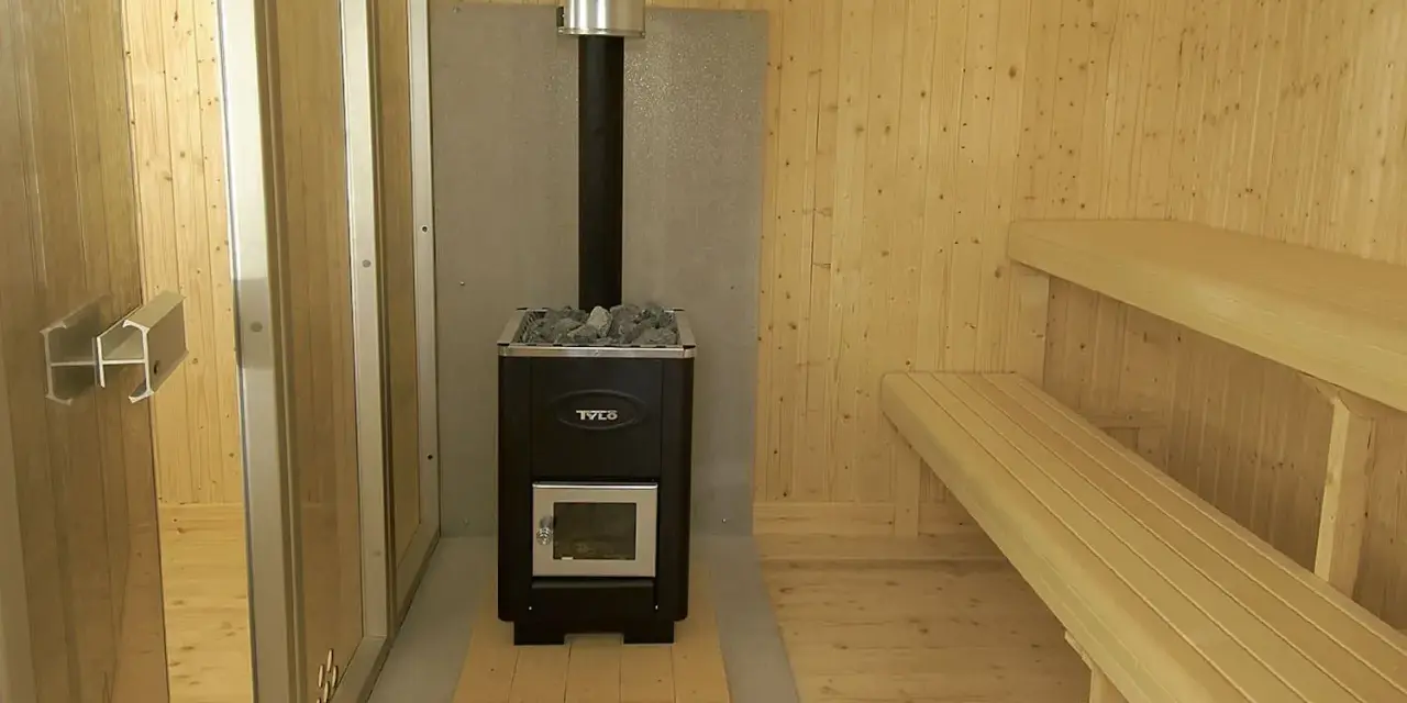 En nybyggd bastu utomhus med vedkamin, stenar och träbänkar. Perfekt för avkoppling.