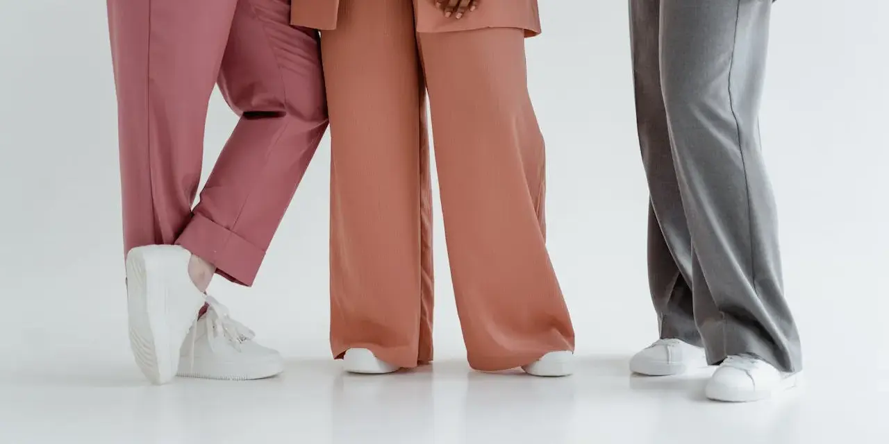 Trzy kobiety w eleganckich stylizacjach. Jedna w różowych spodniach i marynarce, druga w brzoskwiniowym garniturze, trzecia w szarych spodniach. Jaka marynarka do szarych spodni?