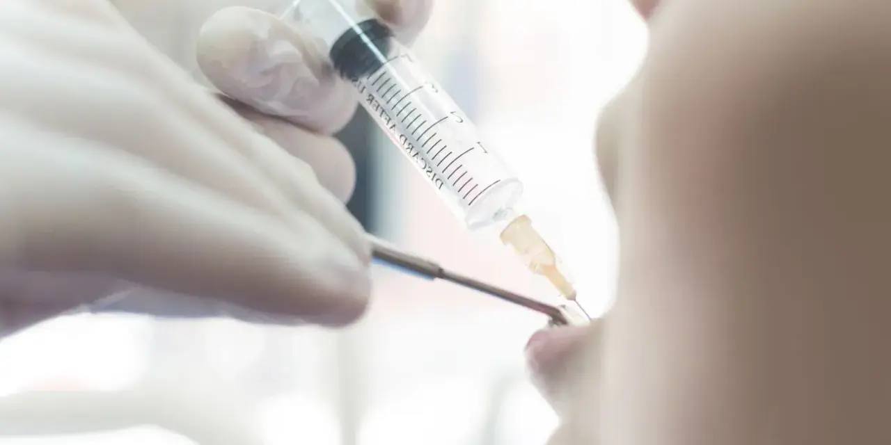 Dentysta podaje znieczulenie pacjentowi strzykawką.