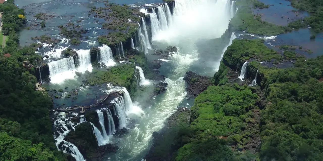 An aerial view of Iguazu Falls, a breathtaking cascade of water surrounded by lush green jungle. A perfect destination for 2 days of unforgettable adventure.