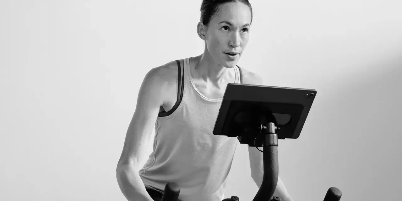 Focused woman powering through a hiit cycle workout on a stationary bike, her muscles engaged.