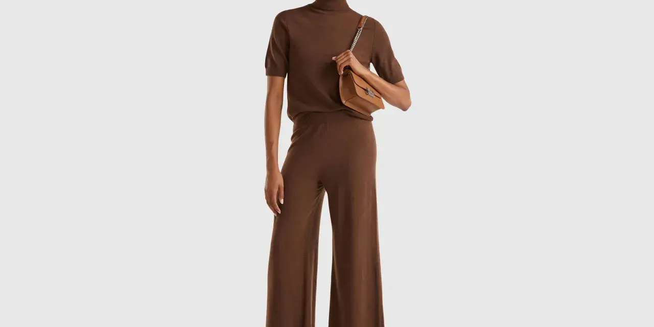 Mujer con conjunto marrón de cuello alto y pantalón ancho, bolso camel. Colores que combinan con el marrón, como el camel, resaltan la elegancia.