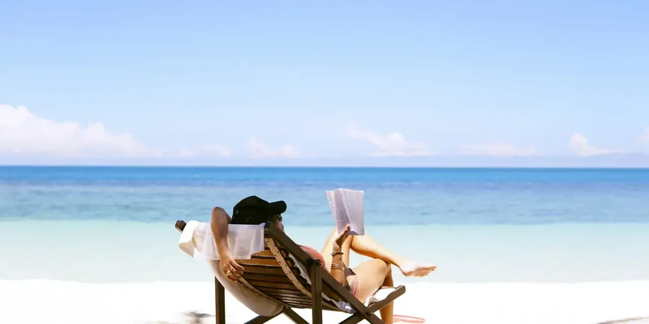 Person entspannt sich lesend am Strand. Ein Traum für jeden Praktikanten, der seinen Urlaubsanspruch genießt.