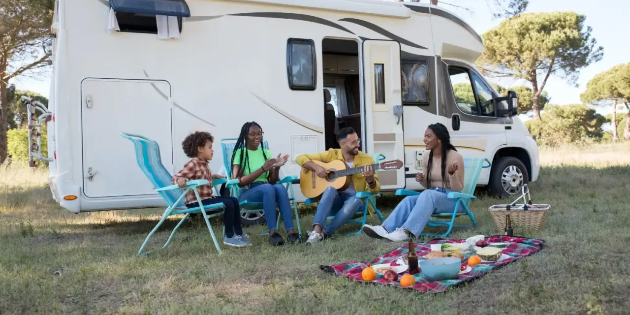 Eine Familie genießt das Camping mit Musik und Picknick vor ihrem Wohnmobil.