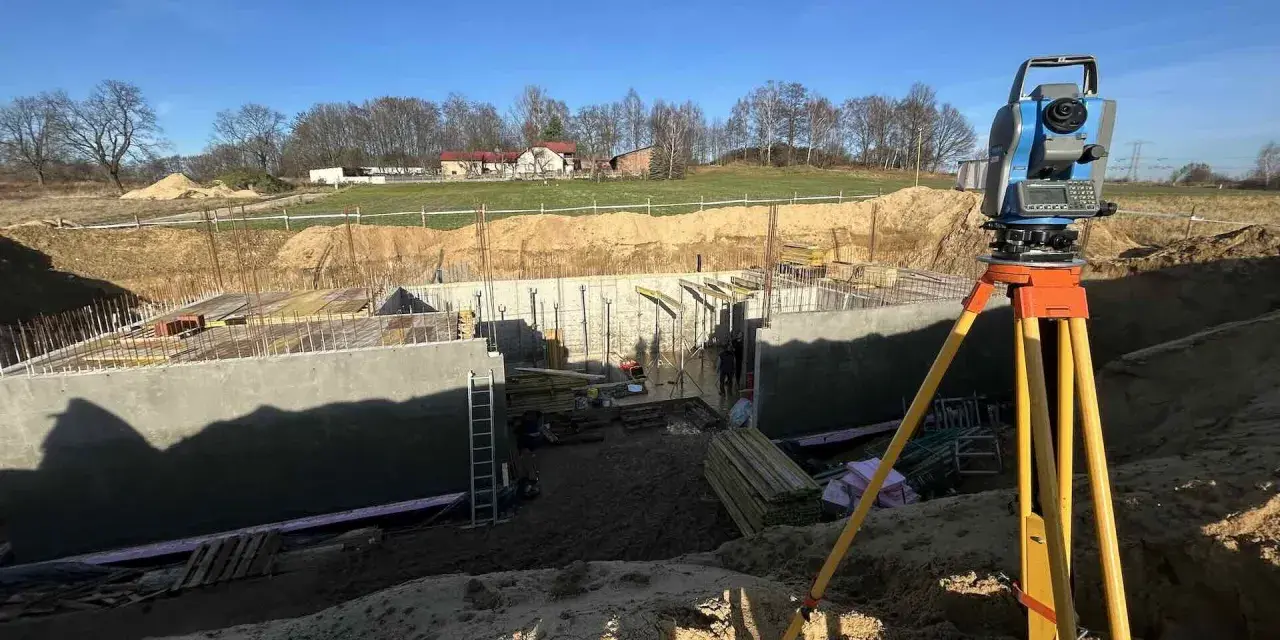 Precyzyjne pomiary geodezyjne na budowie fundamentów. Totalna stacja na statywie gotowa do pracy.
