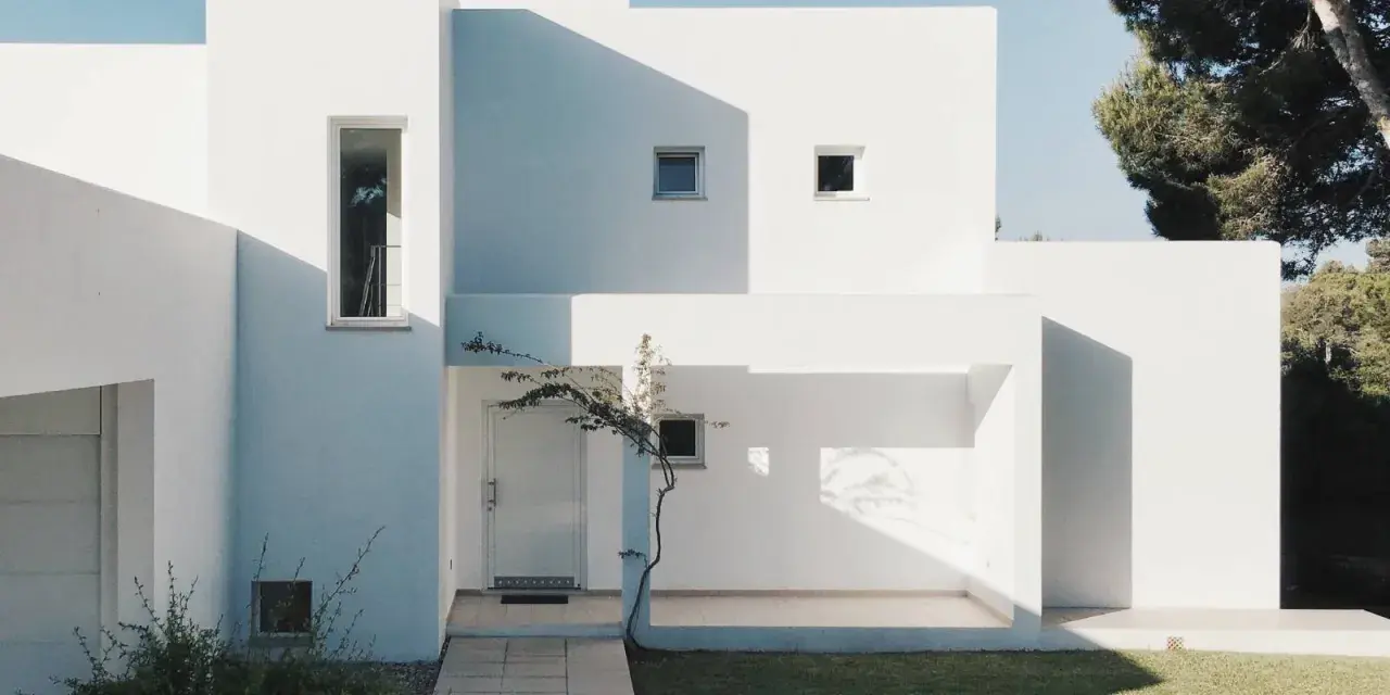 Fachada blanca moderna con sombras marcadas. La mejor pintura para fachadas exteriores protege y embellece esta arquitectura minimalista.