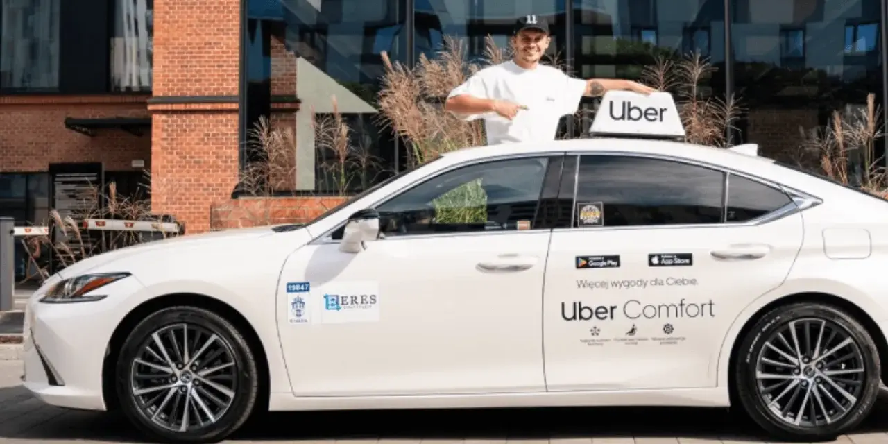 Mężczyzna w czapce z daszkiem stoi obok białego samochodu z logo Uber. To część floty Uber, gotowa do jazdy.