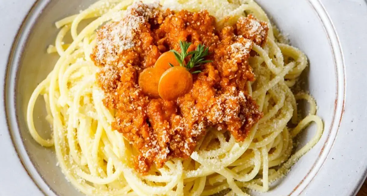 Spaghetti Bolognese, zubereitet im Thermomix, mit Karottenscheiben und Petersilie garniert.