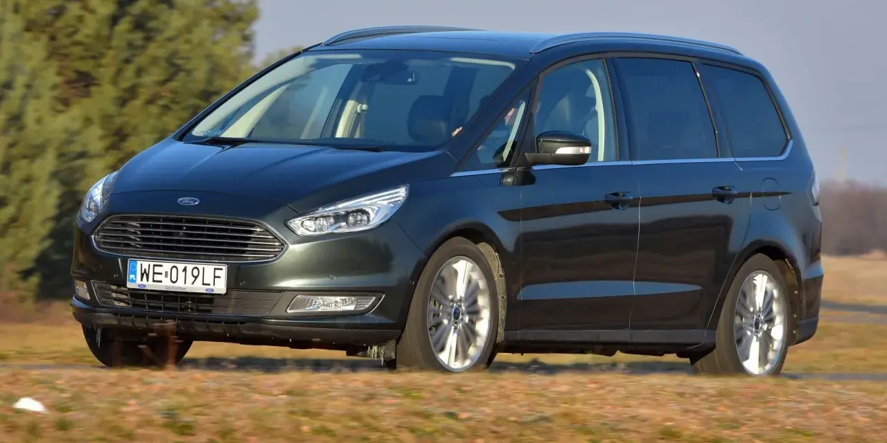 Ciemnozielony Ford Galaxy MK3 w ruchu, z polską tablicą rejestracyjną WE 019LF, przemierza wiejskie drogi.