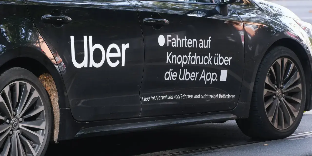 Schwarzes Auto mit "Uber" Logo. Hier erfährst du, wie kann man über Fahrer werden und Fahrten über die App buchen.