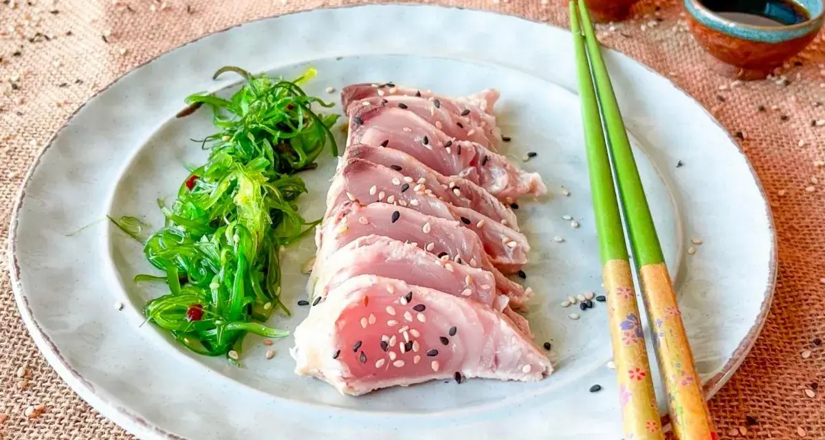 Tataki de bonito, finas lonchas de pescado crudo con semillas de sésamo, acompañadas de ensalada de algas.